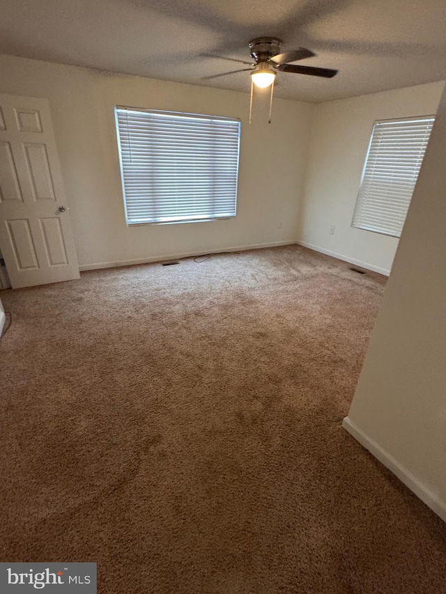 carpeted empty room featuring ceiling fan and a textured ceiling