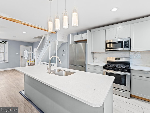 kitchen featuring sink, tasteful backsplash, hanging light fixtures, a center island with sink, and stainless steel appliances