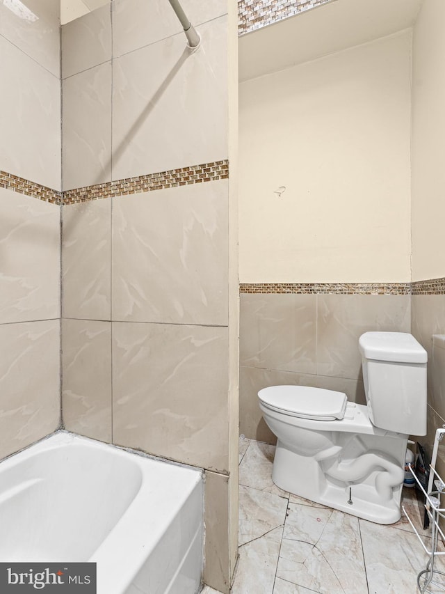 bathroom featuring toilet, tile walls, and a washtub