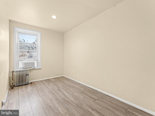 spare room featuring cooling unit, radiator heating unit, and light wood-type flooring