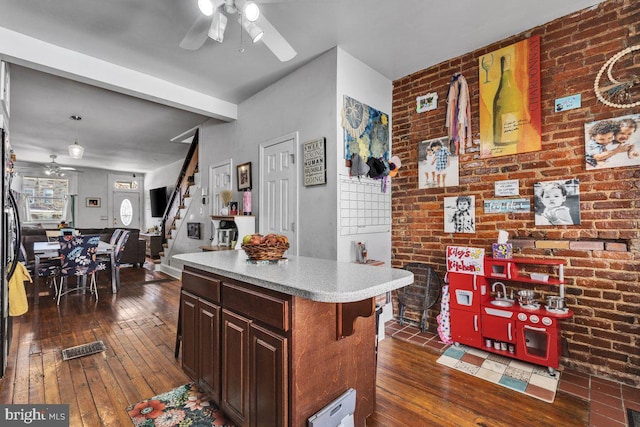 kitchen featuring brick wall, ceiling fan, and dark wood-type flooring