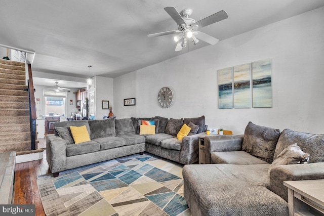 living area featuring a ceiling fan, wood finished floors, and stairs