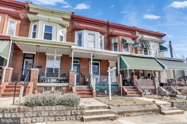 townhome / multi-family property featuring brick siding and a porch