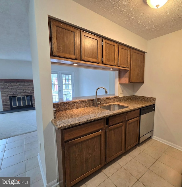 kitchen with sink, light tile patterned flooring, a textured ceiling, and dishwasher