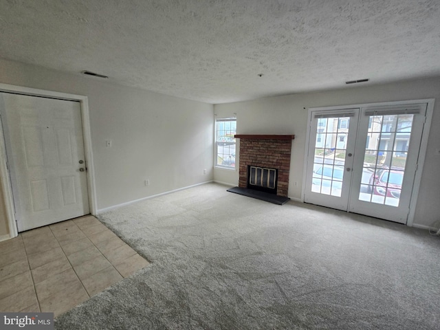 unfurnished living room featuring french doors, a brick fireplace, a textured ceiling, and light carpet