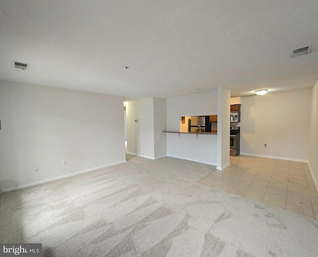 unfurnished living room featuring a textured ceiling and light tile patterned floors