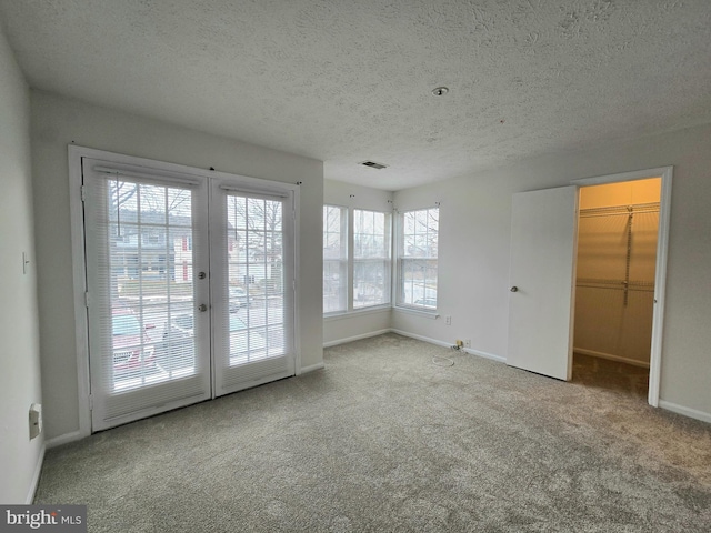 spare room featuring a textured ceiling and light colored carpet