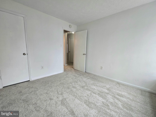 unfurnished bedroom featuring a textured ceiling and light colored carpet