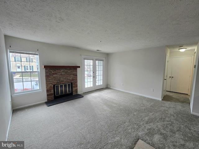 unfurnished living room featuring a textured ceiling, light colored carpet, french doors, and a brick fireplace