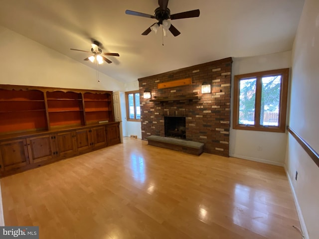 unfurnished living room with a fireplace, ceiling fan, vaulted ceiling, and a wealth of natural light