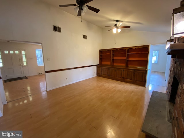 unfurnished living room featuring ceiling fan, light wood-type flooring, a brick fireplace, and high vaulted ceiling