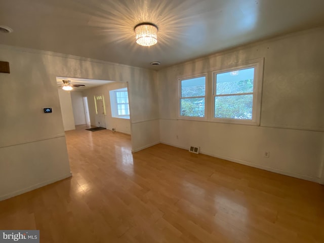 spare room with ceiling fan with notable chandelier and light hardwood / wood-style floors