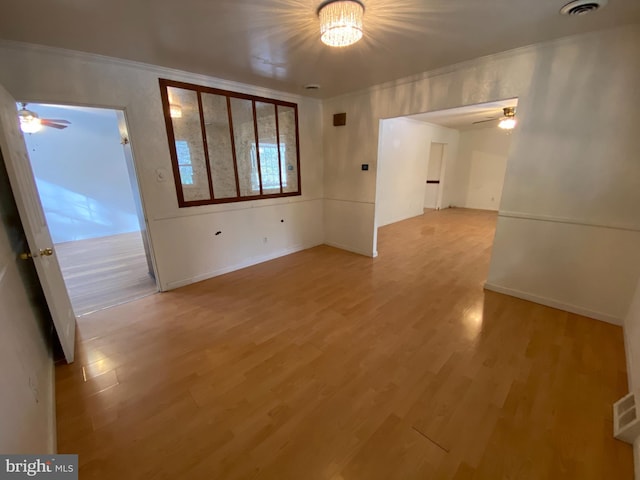 empty room with an inviting chandelier, crown molding, and wood-type flooring