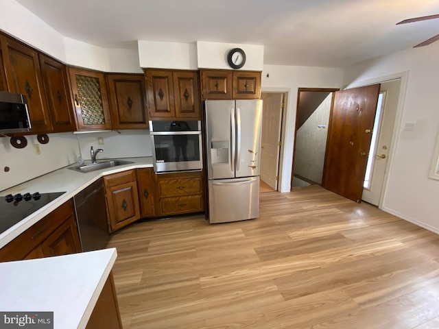 kitchen featuring light wood-type flooring, ceiling fan, black appliances, and sink