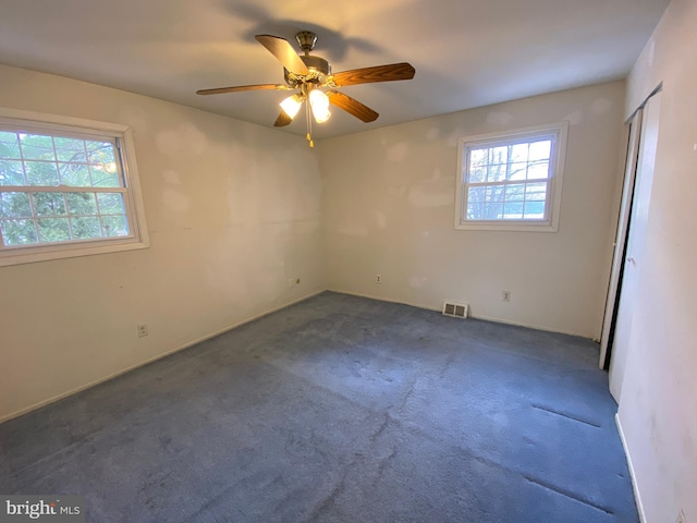 unfurnished room with ceiling fan and dark carpet