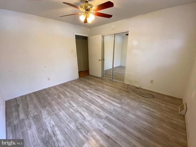 unfurnished bedroom featuring hardwood / wood-style floors, a closet, and ceiling fan