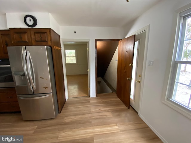 kitchen with light wood-type flooring, stainless steel fridge, and wall oven