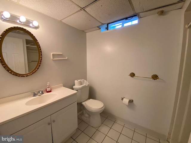 bathroom with a paneled ceiling, toilet, vanity, and tile patterned floors