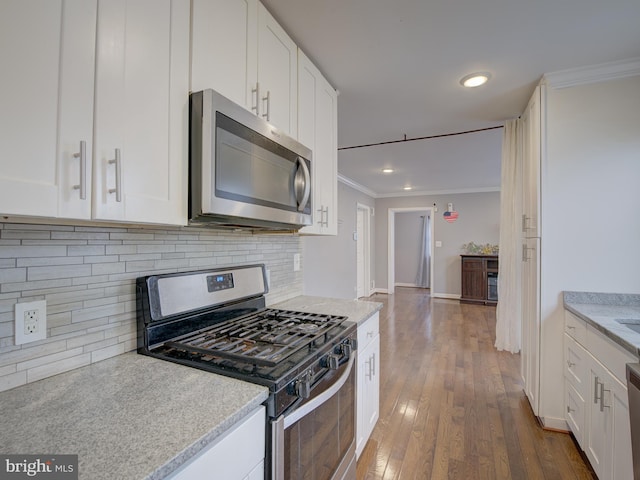 kitchen with appliances with stainless steel finishes, crown molding, white cabinets, and tasteful backsplash