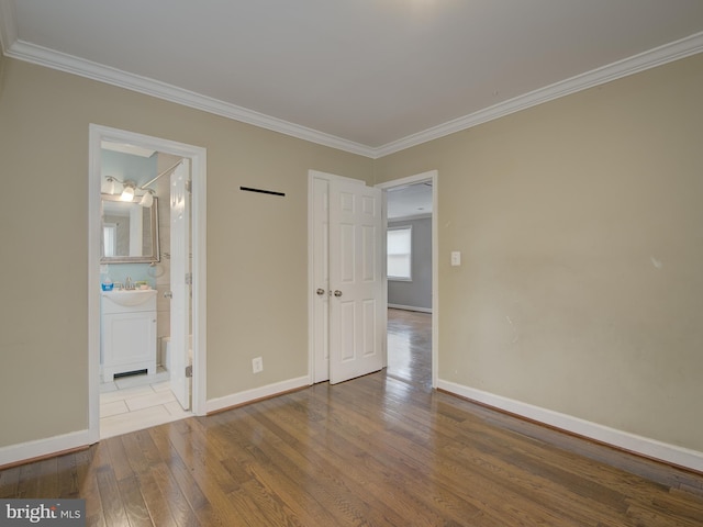 unfurnished bedroom with hardwood / wood-style flooring, sink, ornamental molding, and ensuite bath