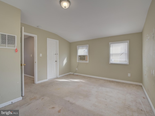 carpeted empty room featuring cooling unit and vaulted ceiling