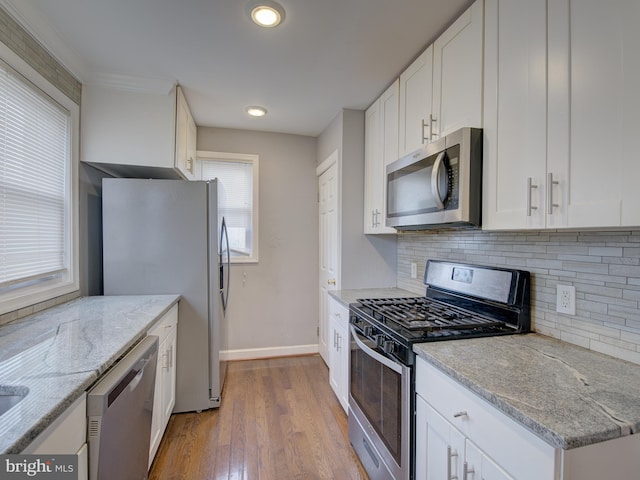 kitchen featuring white cabinetry, stainless steel appliances, decorative backsplash, light hardwood / wood-style flooring, and light stone counters