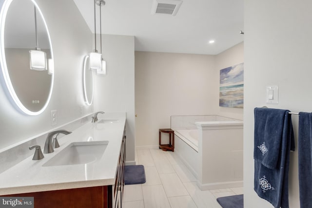 bathroom featuring tile patterned flooring, vanity, and a bath