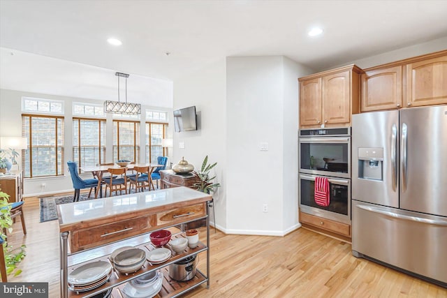 kitchen with light hardwood / wood-style floors, pendant lighting, and stainless steel appliances