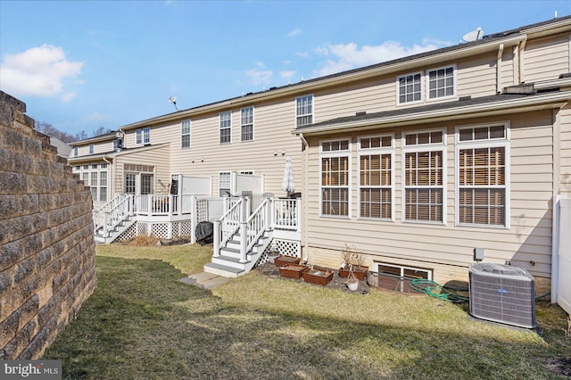 rear view of property with central AC, a wooden deck, and a lawn