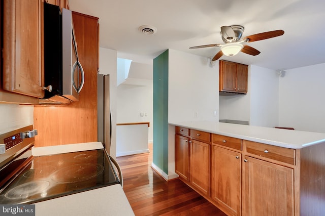 kitchen featuring ceiling fan, dark wood-type flooring, appliances with stainless steel finishes, and kitchen peninsula