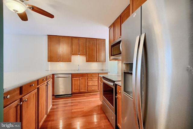 kitchen with ceiling fan, sink, appliances with stainless steel finishes, and light wood-type flooring