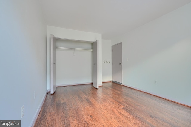 unfurnished bedroom featuring a closet and dark hardwood / wood-style flooring