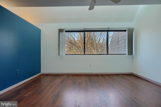 empty room featuring ceiling fan, dark hardwood / wood-style flooring, and vaulted ceiling