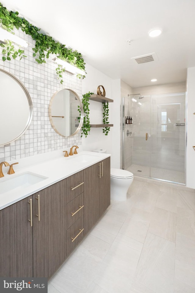 bathroom featuring a shower with shower door, decorative backsplash, vanity, toilet, and tile patterned floors