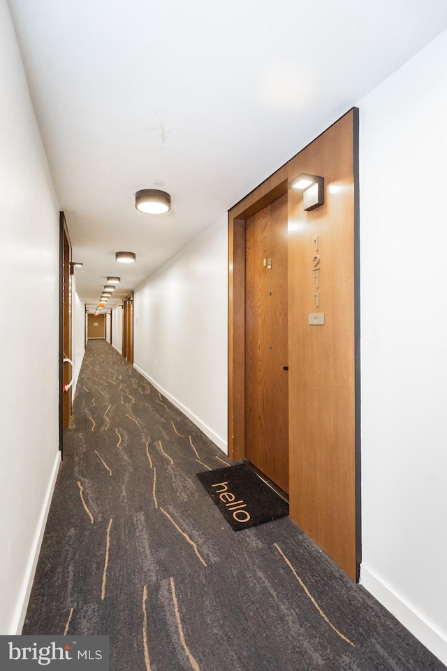 hallway featuring dark colored carpet