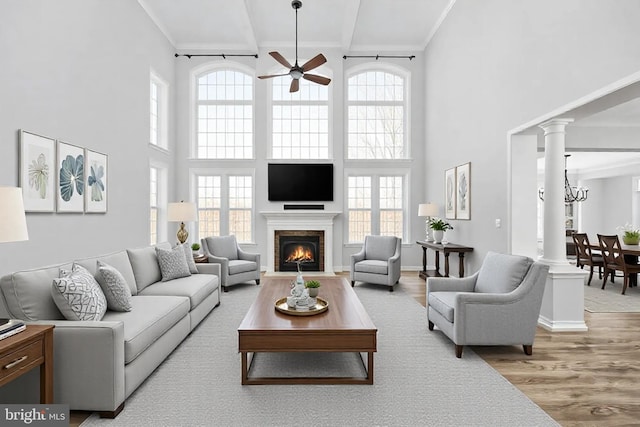 living room with ornate columns, light hardwood / wood-style floors, plenty of natural light, and ceiling fan with notable chandelier