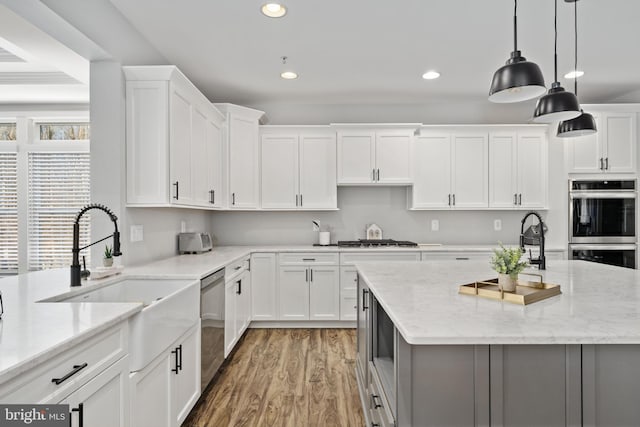 kitchen featuring light stone counters, white cabinetry, stainless steel appliances, and pendant lighting