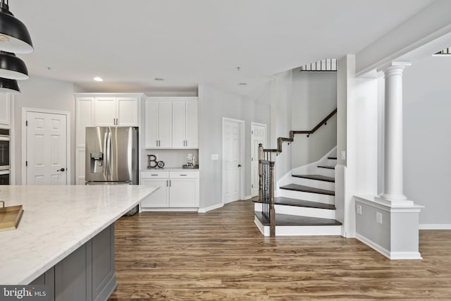 kitchen featuring dark hardwood / wood-style floors, white cabinetry, stainless steel fridge, and light stone counters