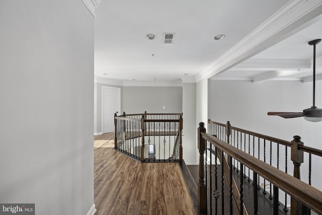 corridor with beam ceiling, ornamental molding, and hardwood / wood-style floors