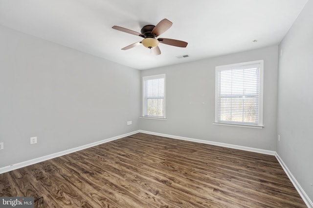 spare room with ceiling fan, a healthy amount of sunlight, and dark wood-type flooring