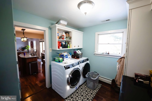 clothes washing area featuring washer and dryer, cabinets, dark wood-type flooring, and a baseboard radiator