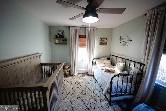 bedroom with multiple windows, wood-type flooring, and ceiling fan