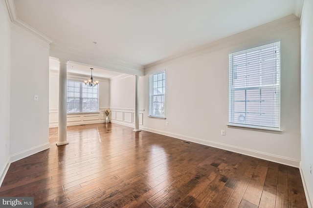 unfurnished room featuring ornate columns, a wealth of natural light, crown molding, and a notable chandelier