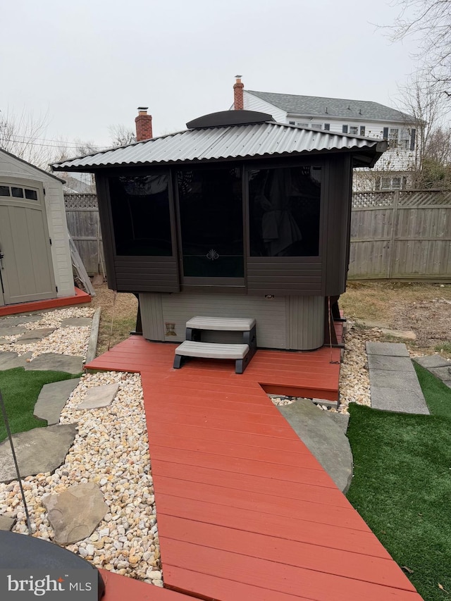 wooden terrace featuring a jacuzzi and a storage shed