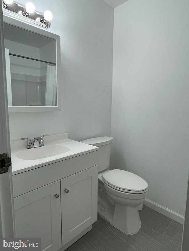 bathroom with toilet, vanity, and a shower with shower curtain