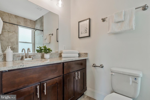 bathroom featuring tiled shower, vanity, and toilet