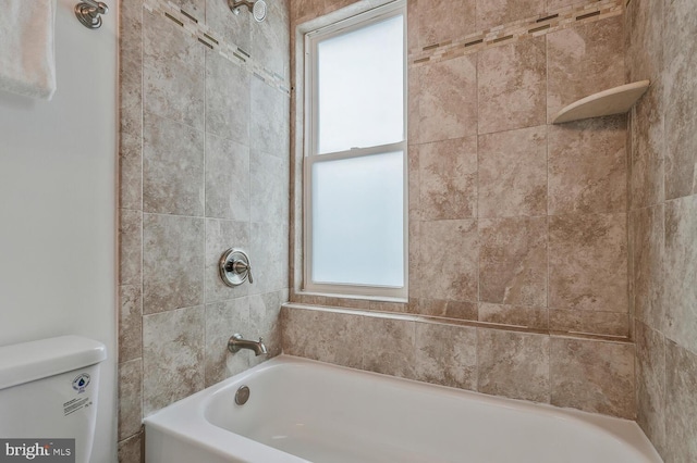 bathroom with toilet and tiled shower / bath