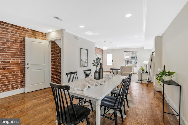 dining room with light hardwood / wood-style flooring and brick wall