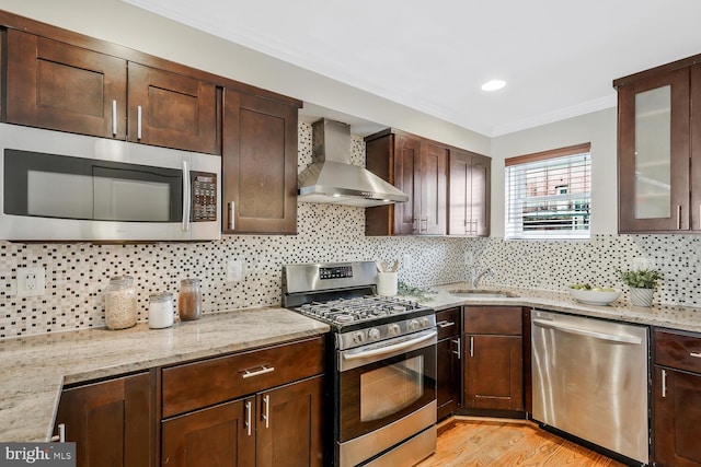 kitchen with backsplash, stainless steel appliances, wall chimney exhaust hood, and sink