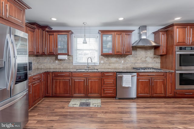 kitchen with light stone countertops, sink, wall chimney exhaust hood, and stainless steel appliances